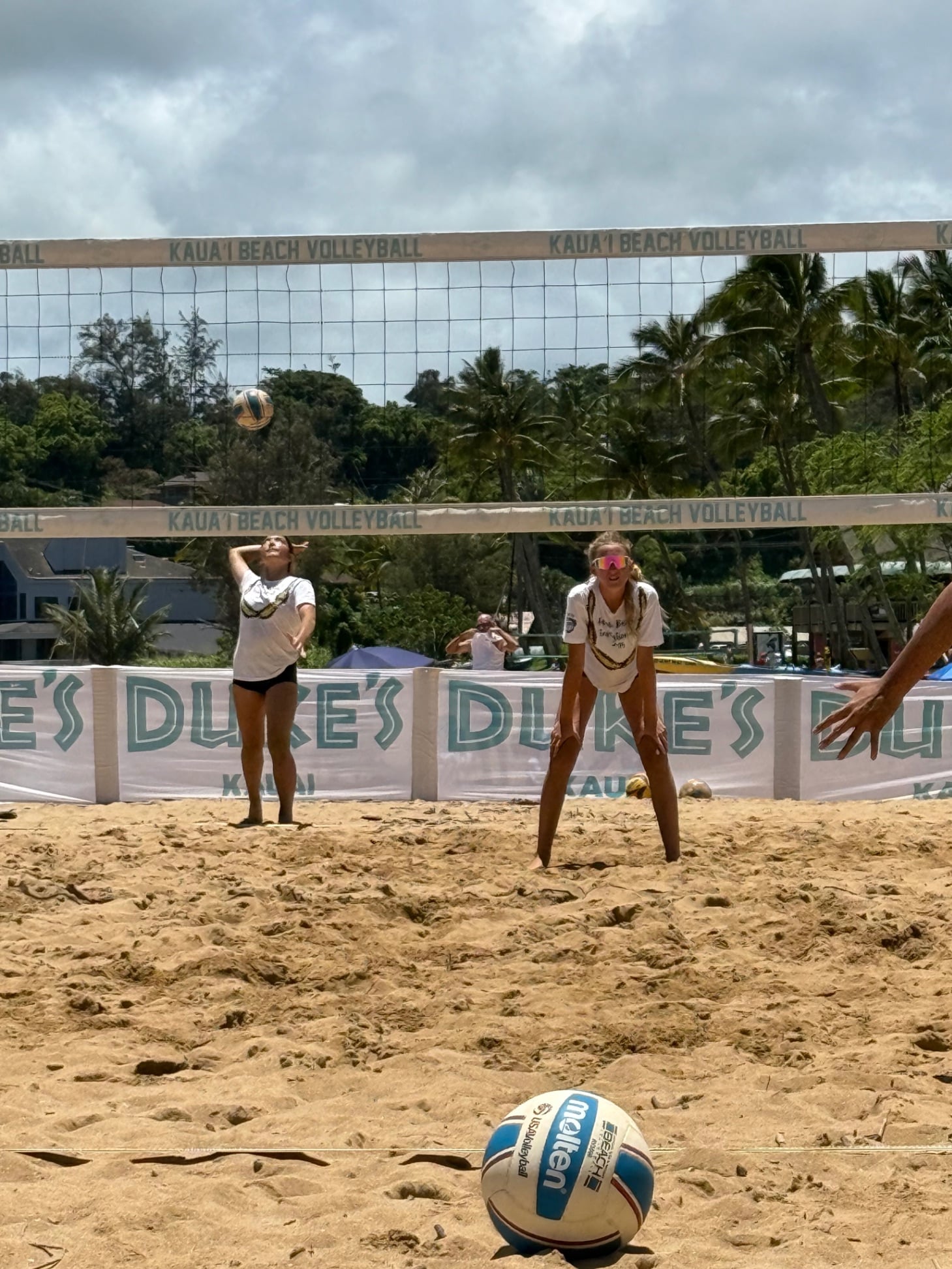 Youth volleyball players training on a sand court with a coach